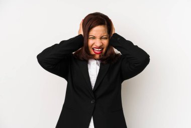 Middle age latin business woman isolated covering ears with hands trying not to hear too loud sound.