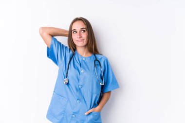 Young nurse woman isolated touching back of head, thinking and making a choice.