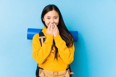 Young chinese backpacker woman isolated laughing about something, covering mouth with hands.
