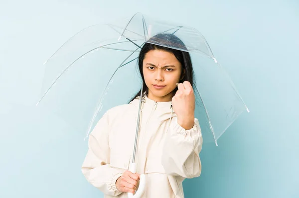 Young chinese woman holding an umbrella isolated laughing and having fun.