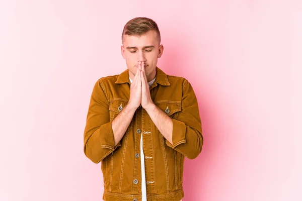 Young Caucasian Man Isolated Holding Hands Pray Mouth Feels Confident — Stockfoto