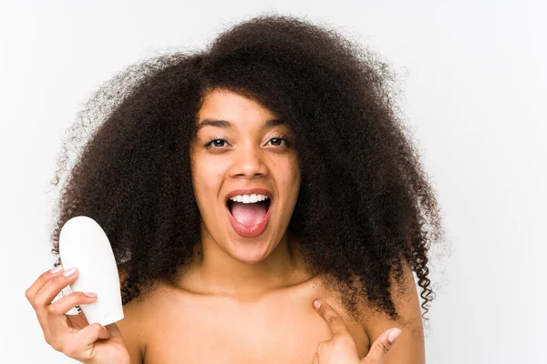 Joven Afro Mujer Sosteniendo Una Crema Hidratante Aislado Sorprendido Apuntando —  Fotos de Stock