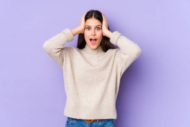 Mor arka planda izole edilmiş genç beyaz bir kadın çığlık atıyor, çok heyecanlı, tutkulu, bir şeyden memnun..