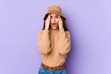 Mor arka planda izole edilmiş beyaz bir kadın yüzünün yarısını palmiye ile kaplarken eğleniyor..