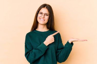 Beyaz tenli genç bir kadın, bej arka planda izole edilmiş. Elinde bir fotokopi odası olduğu için heyecanlı..