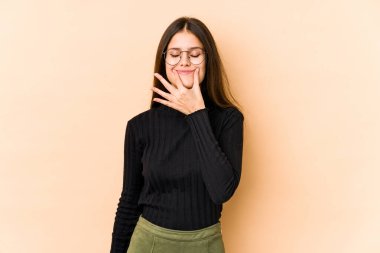 Beyaz tenli genç bir kadın bej arka planda izole edilmiş. İki seçenek arasında şüpheyle bakıyor..