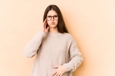 Bej arka planda izole edilmiş genç beyaz kadın yanaklarına üflüyor, yorgun bir ifadesi var. Yüz ifadesi kavramı.