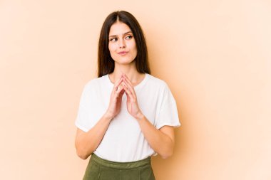 Kafkasyalı genç bir kadın, bej arka planda izole edilmiş, bir plan hazırlıyor..