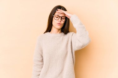 Beyaz tenli genç bir kadın bej arka planda izole edilmiş tapınaklara dokunuyor ve baş ağrısı çekiyor..