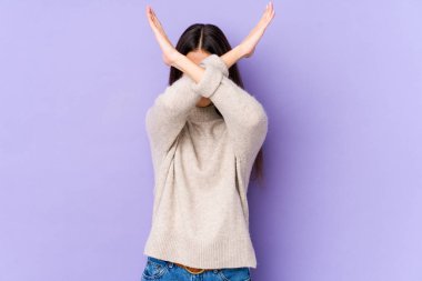 Mor arka planda izole genç beyaz kadın iki kolu çapraz tutuyor, inkar kavramı.