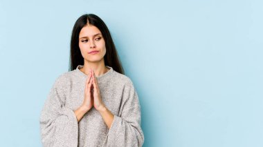 Kafkasyalı genç bir kadın mavi arka planda izole edilmiş bir plan kuruyor, bir fikir kuruyor..