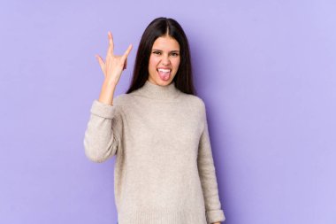 Mor arka planda izole edilmiş genç beyaz kadın parmaklarıyla taş hareketi gösteriyor.