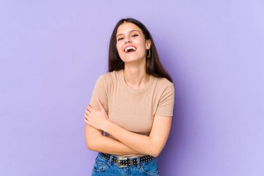 Mor arka planda izole edilmiş genç beyaz kadın gülüyor ve eğleniyor..