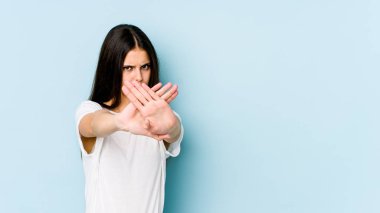 Mavi arka planda izole edilmiş genç beyaz kadın elini uzatmış, dur işareti göstererek seni engelliyor..