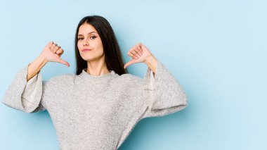 Mavi arka planda izole genç beyaz kadın gururlu ve kendinden emin hissediyor, örnek olarak..