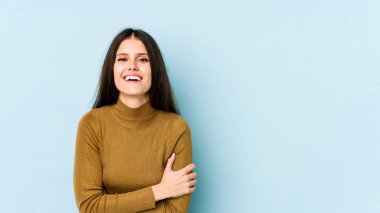 Genç beyaz kadın mavi arka planda izole edilmiş gülüyor ve eğleniyor..