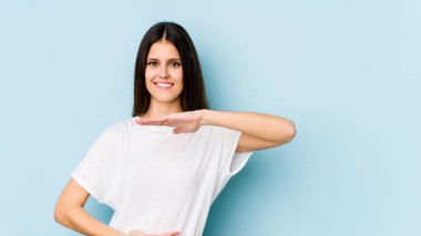 Mavi arka planda izole edilmiş beyaz bir kadın iki eliyle bir şey tutuyor, ürün sunumu..