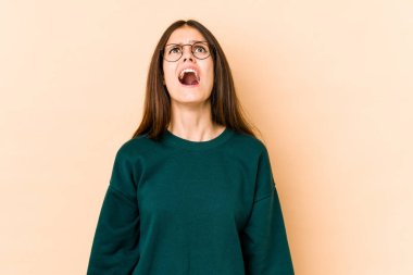 Beyazlı genç bir kadın bej arka planda izole edilmiş çok kızgın, öfkeli, hayal kırıklığına uğramış.