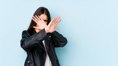 Mavi arka planda izole edilmiş genç beyaz kadın iki kolu çapraz tutuyor, inkar kavramı.