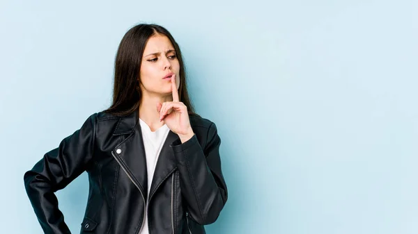 stock image Young caucasian woman isolated on blue background keeping a secret or asking for silence.