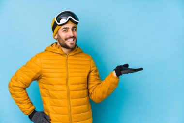 Beyaz tenli genç kayakçı, avucunun içinde fotokopi alanı gösteriyor ve belinde bir el daha tutuyor..