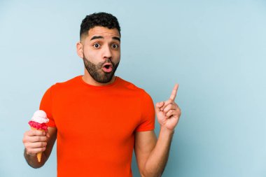 Elinde dondurma tutan genç latin adam yalıtılmış bir şekilde kenarı işaret ediyor.
