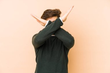 Genç Arap bir adam bej bir arka planda izole edilmiş iki kolu çapraz tutuyor, inkar kavramı.