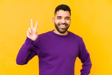 Genç, melez Arap bir adam zafer işareti gösteriyor ve gülümsüyor..