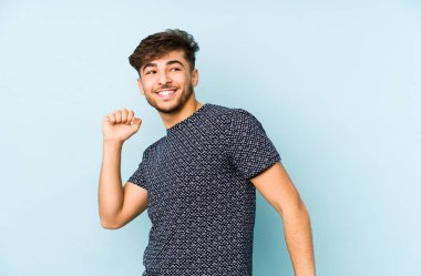 Genç Arap adam mavi arka planda izole edilmiş dans ediyor ve eğleniyor..