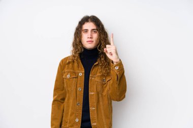 Uzun saçlı adam yalnız poz veriyor. Bir numarayı parmağıyla gösteriyor..