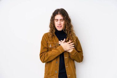 Uzun saçlı adam yalnızmış gibi gülüyor, elleri kalbinde, mutluluk kavramında tutuyor..