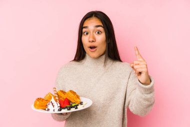 Genç Asyalı kadın bir waffle tutuyor. Bir fikri var, ilham verici bir kavram..