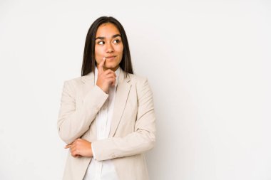 Beyaz bir arka planda izole edilmiş genç bir kadın şüpheli ve şüpheci bir ifadeyle yana bakıyor..