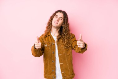 Genç, uzun saçlı, yalnız poz veren neşeli gülümsemeler öne bakıyor..