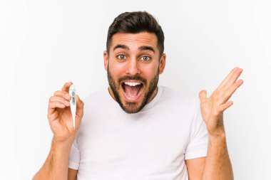 Elinde termometre tutan beyaz bir genç Kafkasyalı zafer ya da başarı kutlaması yapıyor.