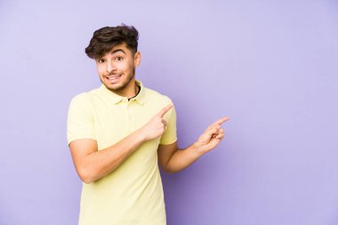 Mor arka planda izole edilmiş genç bir Arap adam işaret parmağıyla bir fotokopi alanını işaret ederek şok oldu..