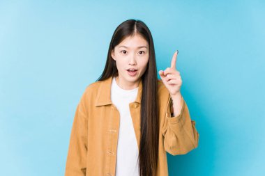 Mavi arka planda poz veren Çinli genç bir kadın bir fikri, ilham konsepti var..