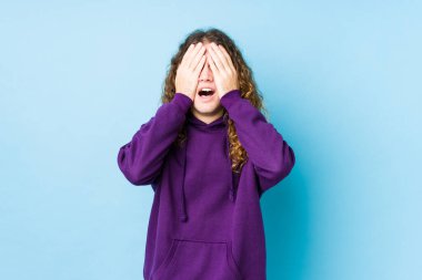 Uzun saçlı adam yalnız poz veriyor. Gözleri ellerle kaplıyor. Gülümsüyor ve bir sürpriz bekliyor..