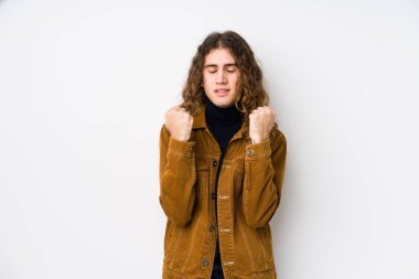 Uzun saçlı adam münzevi poz veriyor, yumruğunu kaldırıyor, mutlu ve başarılı hissediyor. Zafer konsepti.