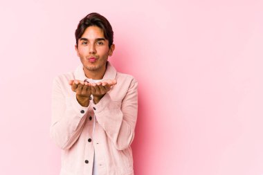 Pembe arka planda poz veren genç, beyaz bir adam izole edilmiş dudaklar ve hava öpücüğü göndermek için avuç içleri tutuyor..