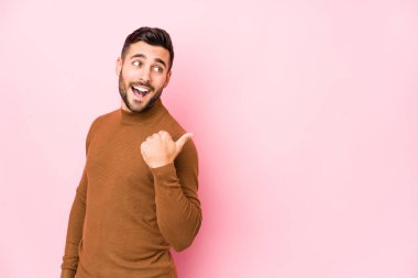 Pembe arka planda genç, beyaz bir adam parmak kadar uzakta izole noktalar, gülüyor ve kaygısız.