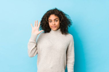 Genç Afro-Amerikan kıvırcık saçlı kadın gülümseyerek beş numarayı parmaklarıyla gösteriyor..