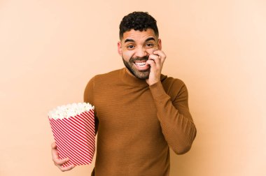 Patlamış mısır tutan genç latin adam tırnak yiyor, gergin ve çok endişeli..