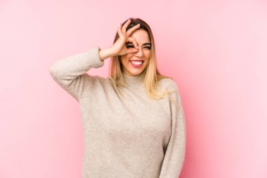 Middle age woman over isolated background excited keeping ok gesture on eye.