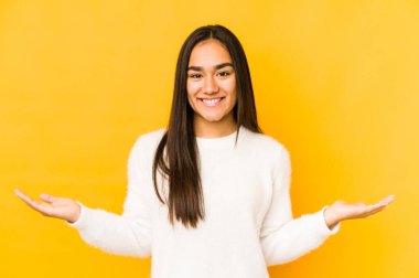 Sarı arka planda izole edilmiş genç bir kadın hoş bir ifade sergiliyor..