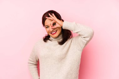 Orta yaşlı Latin bir kadın pembe arka planda izole edilmiş. Heyecanlı..