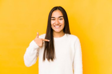 Sarı arka planda yaşayan genç bir kadın gömlek fotokopi odasını elle işaret ediyor, gururlu ve kendinden emin