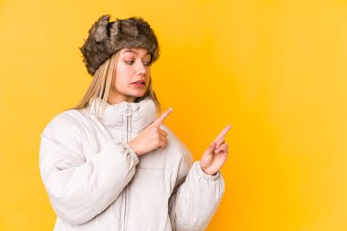 Kışlık giysiler giyen genç beyaz kadın işaret parmağıyla fotokopi alanını işaret ederek şok oldu..