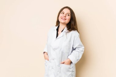 Genç doktor gülümseyerek, neşeli ve keyifli bir şekilde yana bakıyor..