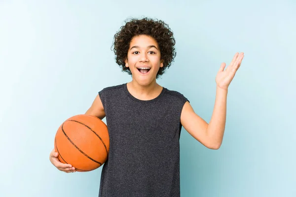 男孩在蓝色背景下孤身一人打篮球 得到了一个愉快的惊喜 兴奋和举手 — 图库照片